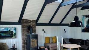 Una sala de estar acogedora con chimenea, un sofá, una mesa de comedor y un amplio ventanal.