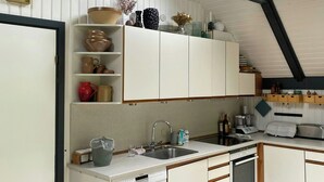 Una cocina con armarios blancos, lavavajillas, un lavamanos y una ventana sobre la encimera.