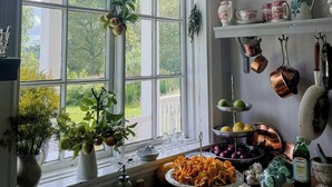A kitchen with a large window, a sink, and various kitchen items on the counter. - Converted school in Östergötland oak landscape (Tjällmo)