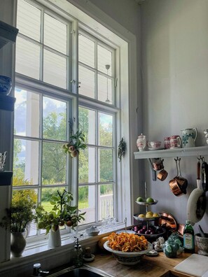 A kitchen with a large window, a sink, and various kitchen items on the counter. - Converted school in Östergötland oak landscape (Tjällmo)