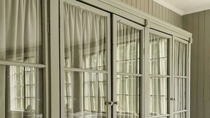 A room with a large, light-colored wardrobe with multiple doors and windows, each with curtains. - Converted school in Östergötland oak landscape (Tjällmo)