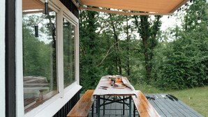 A wooden deck with a table and benches, overlooking a lush green forest. - Adorable retro home with lovely terrace (Bryrup)