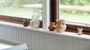 A window with a view of greenery, a wooden table, and three ceramic pots on the sill. - Adorable retro home with lovely terrace (Bryrup)