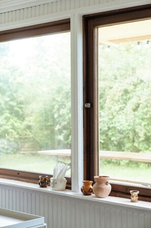 A window with a view of greenery, a wooden table, and three ceramic pots on the sill. - Adorable retro home with lovely terrace (Bryrup)