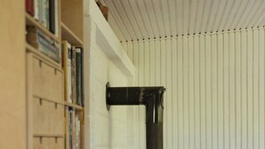 A room with a wood-burning stove, bookshelves, and a bed. - Adorable retro home with lovely terrace (Bryrup)