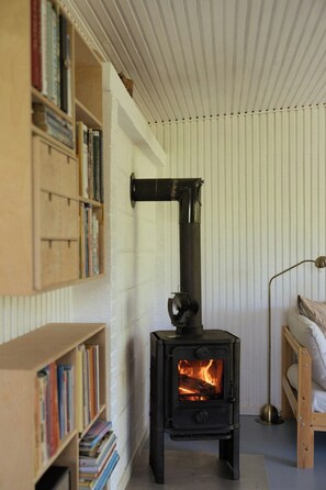 A room with a wood-burning stove, bookshelves, and a bed. - Adorable retro home with lovely terrace (Bryrup)