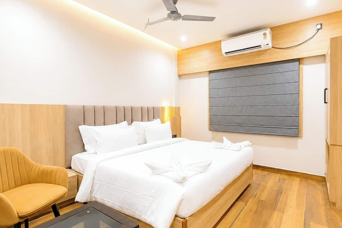 Una habitación de hotel con cama, una silla, una mesa, un ventilador de techo y un equipo de aire acondicionado.