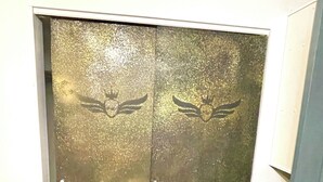 En metalldörr till hissen med en reflekterande yta och ett nyckelhål.