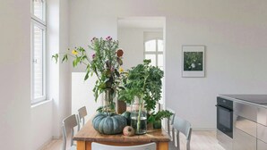Une table à manger avec des chaises, un coin cuisine et un tableau encadré au mur.