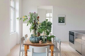 Ein Esstisch mit Stühlen, eine Küchenzeile und ein gerahmtes Bild an der Wand.