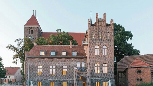 Un grand bâtiment en briques, doté d’une tour imposante, de nombreuses fenêtres et d’une entrée en pierre.