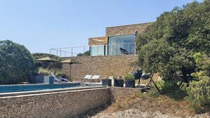 Ein modernes Gebäude mit Natursteinverkleidung, einem Swimmingpool und Sitzmöglichkeiten im Freien.