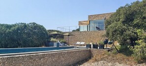 Ein modernes Gebäude mit Natursteinverkleidung, einem Swimmingpool und Sitzmöglichkeiten im Freien.