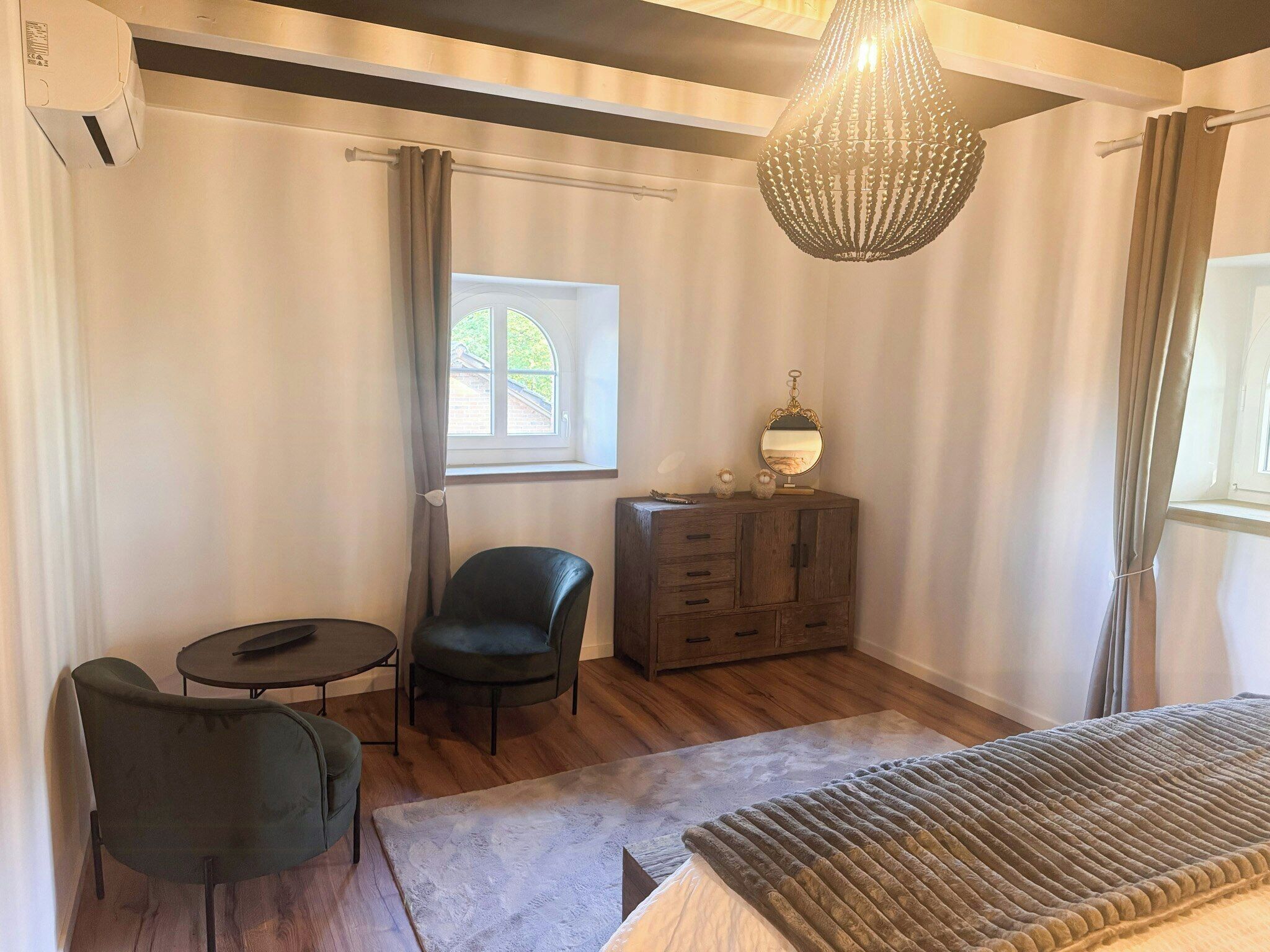 Een kamer met een bed, een houten kast, een stoel, een tafeltje en een kroonluchter.
