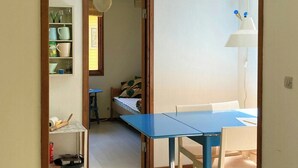 Ein Zimmer mit blauem Tisch und Stühlen, einer weißen Lampe und einem Holztürrahmen.