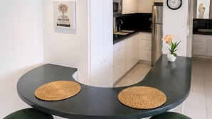 Eine moderne Küche mit weißen Schränken, einer schwarzen Arbeitsplatte und einem Edelstahl-Kühlschrank.