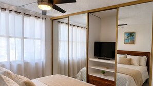 Ein Schlafzimmer mit Bett, Fernseher, Kleiderschrank und Deckenventilator.