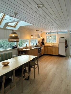 A modern kitchen with wooden cabinets, a dining table, and a skylight. - Hidden gem by Thy National Park (Bedsted)