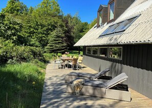 A wooden deck with outdoor furniture, a dining table, and a lounge chair. - Hidden gem by Thy National Park (Bedsted)