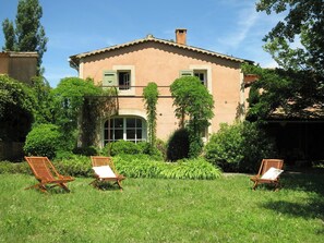 A two-story building with a garden and two wooden lounge chairs. - Provençal villa with Luberon views (Céreste-en-Luberon)