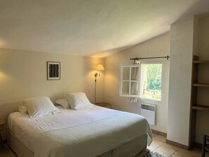 A bedroom with a bed, a bedside lamp, a window with curtains, and a radiator. - Provençal villa with Luberon views (Céreste-en-Luberon)