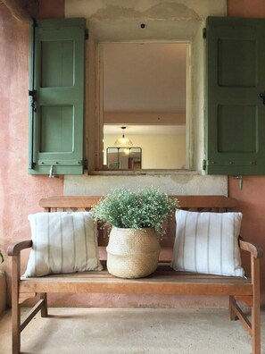 A wooden bench with white cushions, a woven basket with flowers, and a mirror above. - Provençal villa with Luberon views (Céreste-en-Luberon)