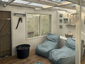 Ein Zimmer mit Holztür, einem Vorhangfenster, einem schwarzen Eimer und einem blauen Sitzsack.