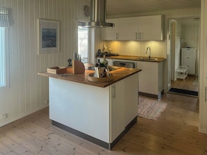 Eine Küche mit Kochinsel, Holz Arbeitsplatten, weißen Schränken und einem integrierten Geschirrspüler.