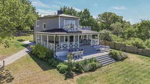 A two-story house with a covered porch and a deck.