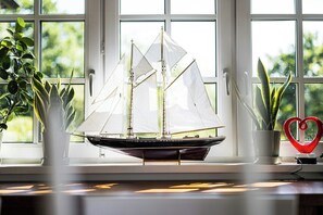 A model sailboat on a windowsill with potted plants and a heart-shaped decoration. - Modern holiday home with view and boat in Aspö (Drottningskär)