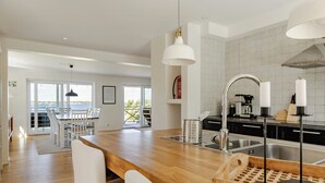 Una cocina moderna con encimera de madera, pileta de acero inoxidable y lámparas colgantes.