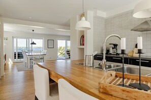 A modern kitchen with a wooden countertop, stainless steel sink, and pendant lights. - Modern holiday home with view and boat in Aspö (Drottningskär)
