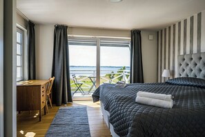 A bedroom with a large bed, a desk, and a view of the outdoors.
