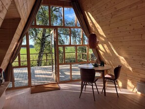 Ein Zimmer mit großem Fenster, einem Tisch, zwei Stühlen und einer Hängeleuchte.
