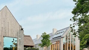 Ein modernes Gebäude mit großen Fenstern und einem strohgedeckten Anbau.