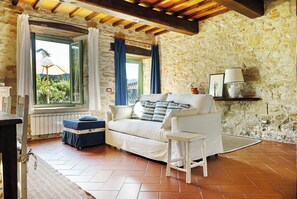 A rustic room with a stone wall, a white sofa, a small table, and a view through a window. - Villa with pool in the heart of Chianti Rufina (Londa)