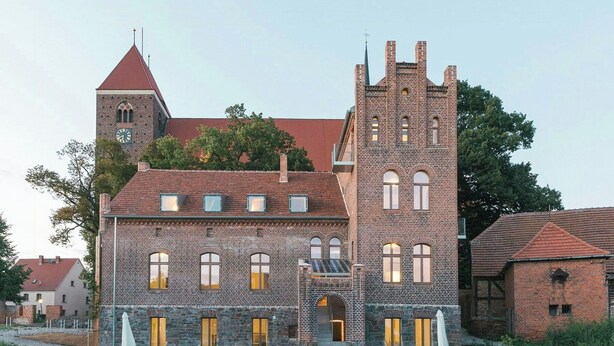 Un edificio histórico con una torre destacada, ventanas de arco y fachada de piedra.