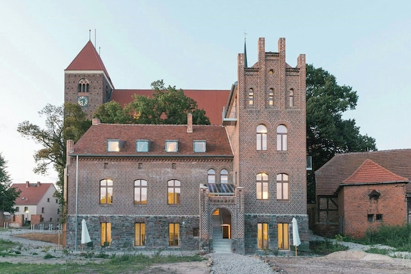 Ein historisches Gebäude mit einem markanten Turm, Bogenfenstern und einer Stein-Fassade.
