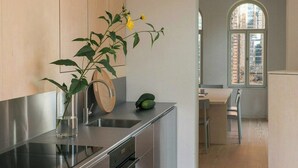 Una cocina moderna con electrodomésticos de acero inoxidable, un protector contra salpicaduras de madera y vistas a través de un ventanal arqueado.