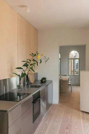 Eine moderne Küche mit Edelstahlgeräten, einer Holzrückwand und Blick durch ein Rundbogenfenster.