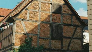 Ein traditionelles Fachwerkhäuschen mit einem steilen Dach, einer Holztreppe und einer Backsteinmauer.