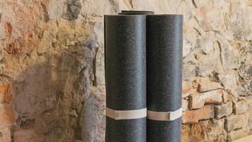 Two cylindrical objects with metal bands on a flat surface against a textured brick wall.