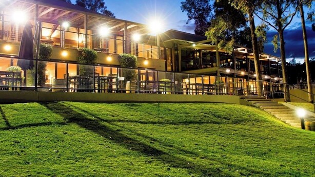 A modern building with a glass facade, outdoor seating, and a well-lit entrance. - Premium 2 Bedroom French Villa + Free Wine Tasting (Pokolbin)