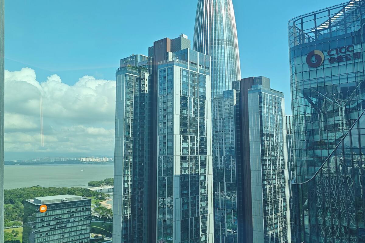 Un edificio de gran altura con una aguja distintiva, rodeado de otros rascacielos modernos.