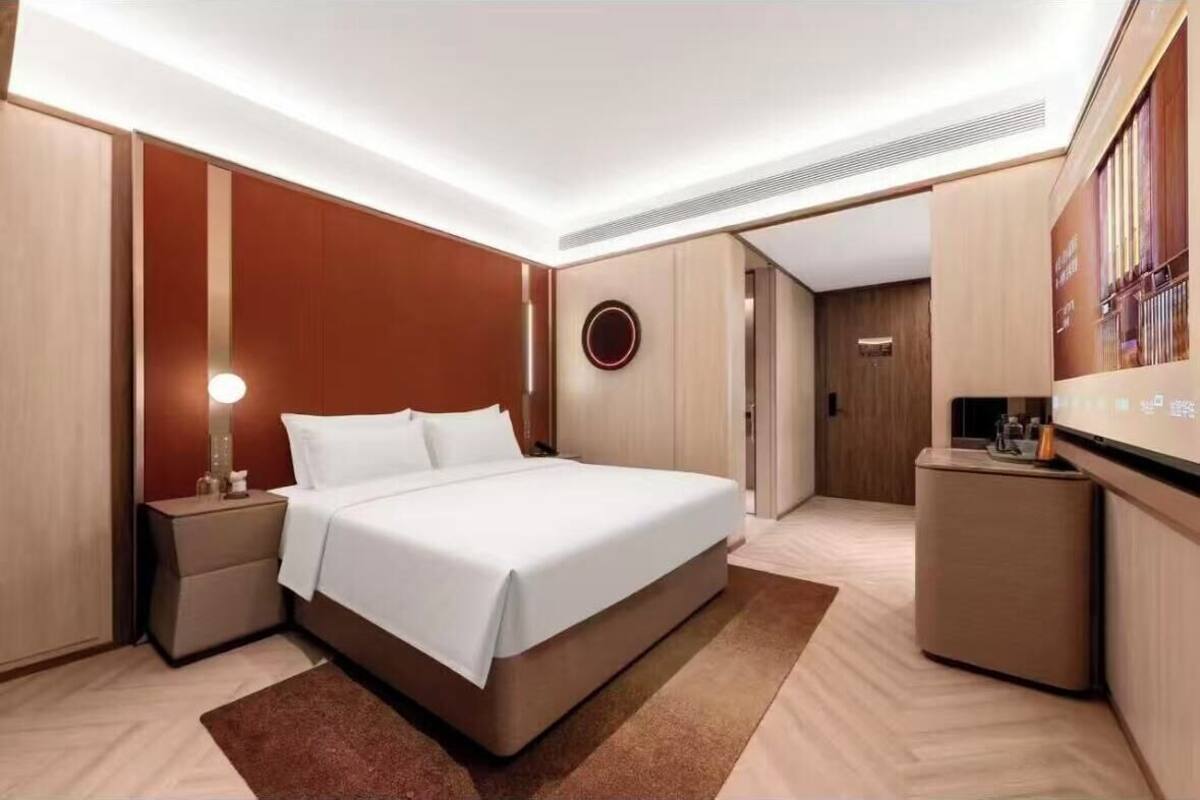 Una habitación de hotel moderna con una cama grande, mesitas de noche, un escritorio y un televisor montado en la pared.