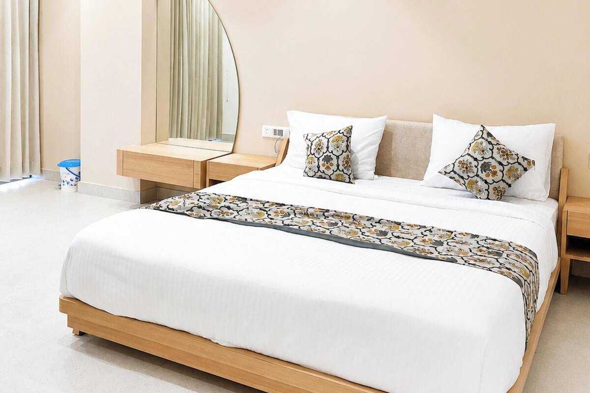 A modern hotel room with a large bed, a ceiling fan, a bedside table, and a mirror.