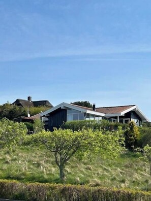 Ein modernes Haus mit Satteldach, umgeben von Grünflächen und weiteren Häusern.
