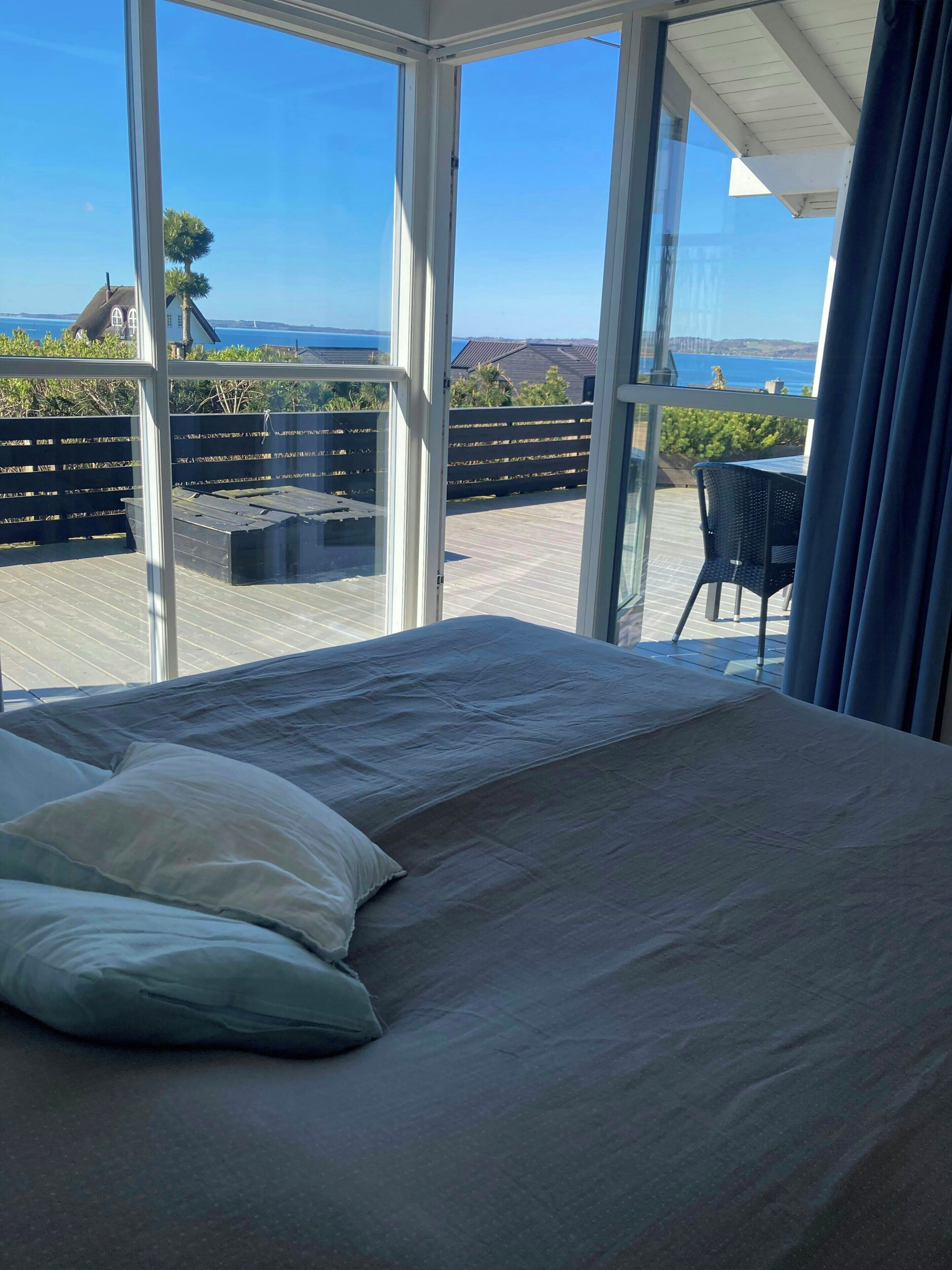 Ein Schlafzimmer mit einem großen Bett, Meerblick und einem Balkon mit Tisch und Stühlen.