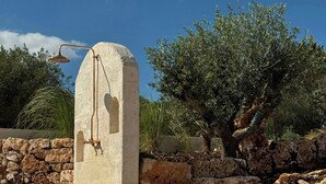 Una estructura de piedra con un accesorio metálico, rodeada de rocas y vegetación.