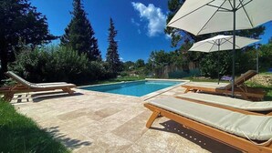 A swimming pool with lounge chairs and umbrellas. - Former silkworm farm from 1871 in Ardèche (Joannas)